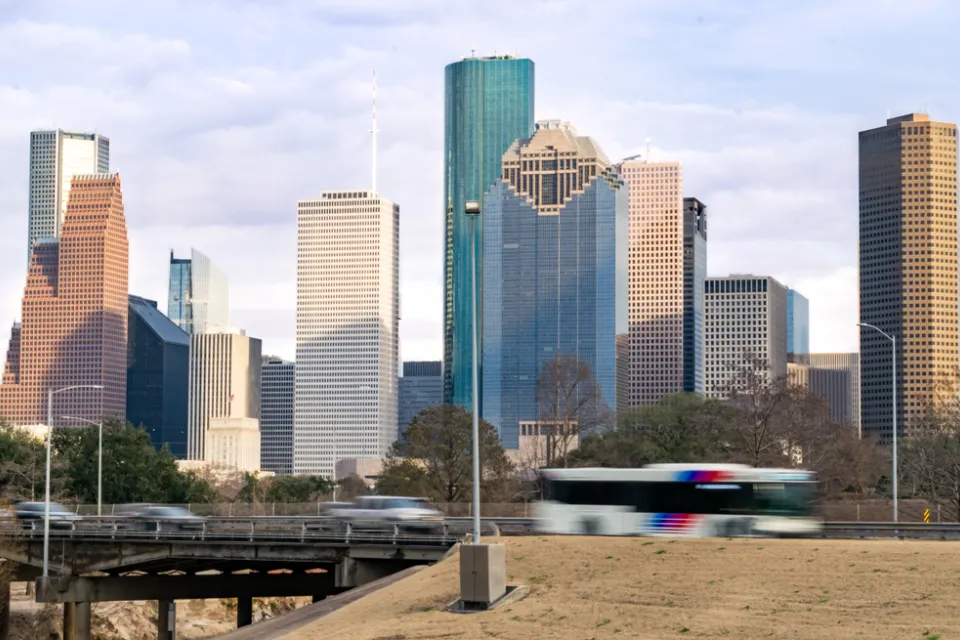 View of Houston freeway with bus, cars, and downtown skyline in background